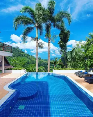 a swimming pool with palm trees in the background at Patong Hill Estate 6 in Patong Beach