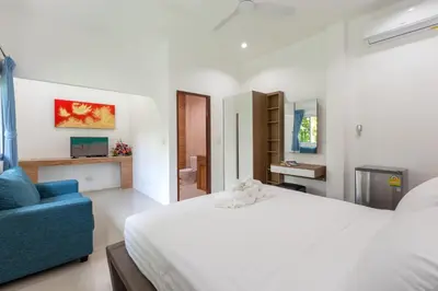 a bedroom with a white bed and a blue chair at Patong Hill Estate 6 in Patong Beach