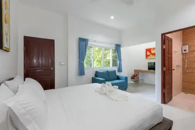 a bedroom with a large white bed and a blue chair at Patong Hill Estate 6 in Patong Beach