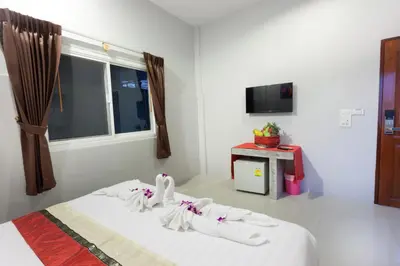 a bedroom with a bed with white sheets and a window at Freedom Hotel in Patong Beach