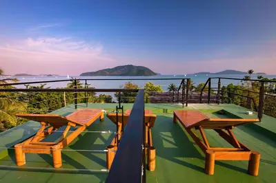 a group of tables and chairs on a deck with the ocean at Amazing 5br, Seaview private PoolVilla by Intira Villas in Rawai Beach