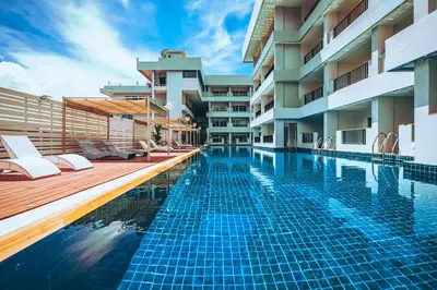 a swimming pool with chaise lounges next to a building at Casa Del M Patong Phuket in Patong Beach