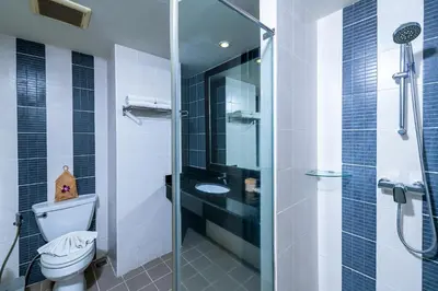 a bathroom with a toilet and a glass shower at Casa Del M Patong Phuket in Patong Beach