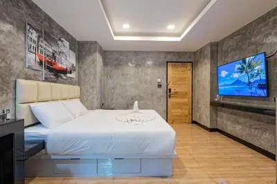 a bedroom with a white bed and a flat screen tv at My Style Resort Hotel -SHA Plus in Patong Beach