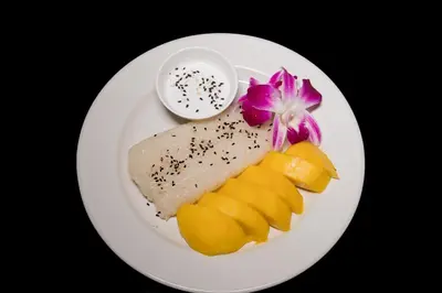 a white plate with a piece of fish and some fruit at Baan Thai Beach Side Residence, Patong Beach in Patong Beach