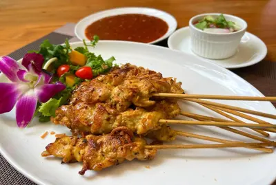 a plate of food with chicken and a salad with chopsticks at Patong Heights in Patong Beach