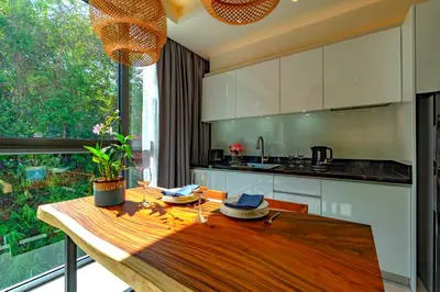 a kitchen with a wooden table and a large window at Patong Heights in Patong Beach