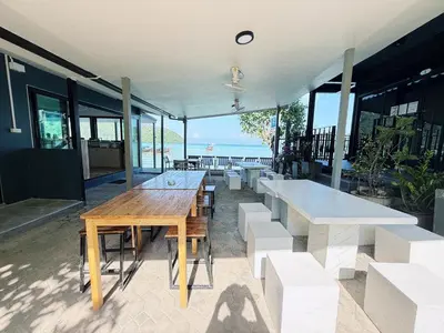 a table and benches on a patio with a view of the ocean at The One Hostel Phi Phi Island in Phi Phi Don