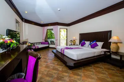 a bedroom with a large bed with purple pillows at Kata Poolside Resort SHA Extra Plus in Kata Beach