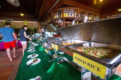 a buffet line with plates of food on a table at Kata Poolside Resort SHA Extra Plus in Kata Beach