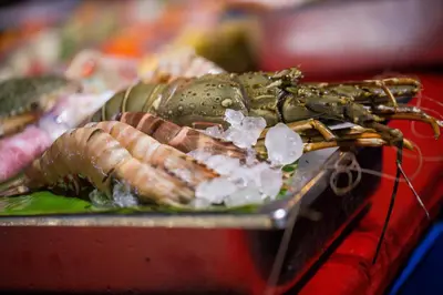 a lobster on a plate of food on a table at Kata Poolside Resort SHA Extra Plus in Kata Beach