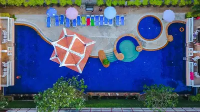 a blue wall with two pools and an umbrella at Kata Poolside Resort SHA Extra Plus in Kata Beach