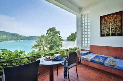 a balcony with a table and chairs and a view of the ocean at Mom Tri's Villa Royale - SHA Plus in Kata Beach