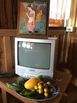 an old television sitting on a table with a plate of fruit at Fisherman Guesthouse in Ko Yao Noi