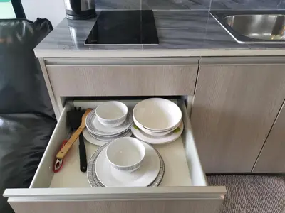 a cabinet with plates and dishes in a kitchen at 5 Floor - Centrio Condominium in Phuket Town - 30 mins to beaches in Phuket Town