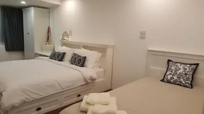 a white bedroom with a large bed and a window at Wora Stay room Kata beach in Kata Beach