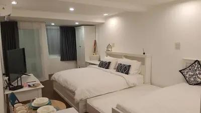 a white bedroom with a bed and a television at Wora Stay room Kata beach in Kata Beach