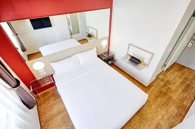 a small room with two beds and a mirror at Easy Planet Phuket Patong in Patong Beach