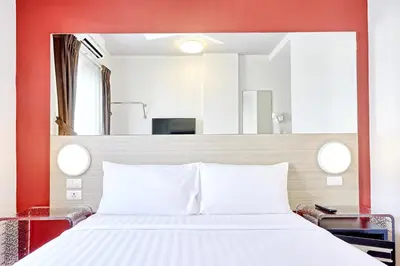 a bedroom with a white bed with a red wall at Easy Planet Phuket Patong in Patong Beach