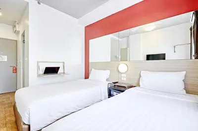 a hotel room with two beds and a mirror at Easy Planet Phuket Patong in Patong Beach