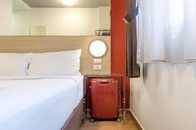a red suitcase sitting next to a bed in a room at Easy Planet Phuket Patong in Patong Beach