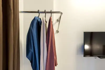 a rack of clothes hanging on a wall next to a tv at Easy Planet Phuket Patong in Patong Beach