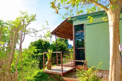 a green house with a porch and a tree at Phi Phi Sea Sky Resort in Phi Phi Don