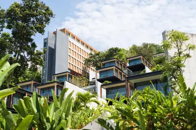 a building with trees on the side of it at The Naka Phuket, a member of Design Hotels in Kamala Beach