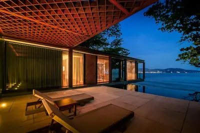 a house with a patio with a table and a bench at The Naka Phuket, a member of Design Hotels in Kamala Beach