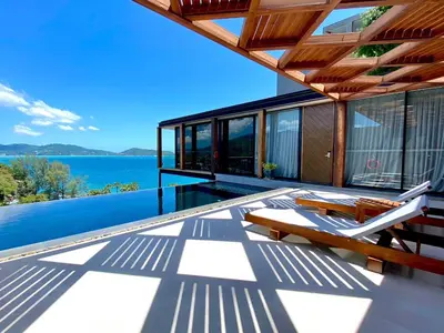 a house with a deck with a view of the water at The Naka Phuket, a member of Design Hotels in Kamala Beach
