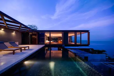 a modern house with a swimming pool at night at The Naka Phuket, a member of Design Hotels in Kamala Beach