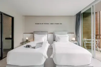 two beds with white sheets in a room at Sugar Ohana Poshtel in Kata Beach