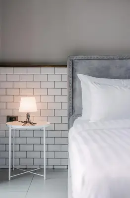 a bed with a table with a lamp on it at Sugar Ohana Poshtel in Kata Beach
