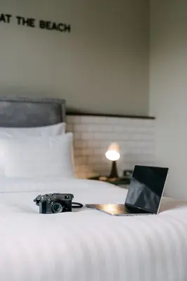 a laptop on a bed with a camera on it at Sugar Ohana Poshtel in Kata Beach