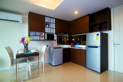 a kitchen with a white refrigerator and a table with chairs at The Aristo by Holy Cow, 2-BR, mountain view in Bang Tao Beach