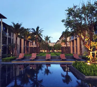 a pool at a resort with chairs and palm trees at Baan mai khao apartment in Mai Khao Beach