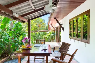 a dining room with a table and chairs on a patio at Thai Style 2BR Villa Nikkie 2 in Nai Harn Beach
