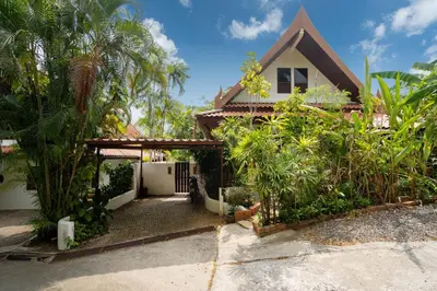 a house with a gate and palm trees at Thai Style 2BR Villa Nikkie 2 in Nai Harn Beach