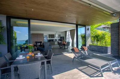 a patio with a table and chairs and a living room at Ocean Rock Kalim in Patong Beach