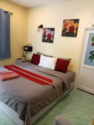 a bedroom with a large bed with red pillows at Airee Mini House in Bang Tao Beach