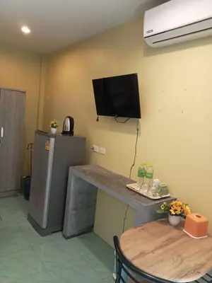 a room with a table and a television on the wall at Airee Mini House in Bang Tao Beach