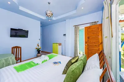 a bedroom with a bed with white sheets and green pillows at RAT VILLA in Ban Pa Khlok