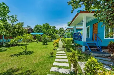 a blue house with a pathway in front of a yard at RAT VILLA in Ban Pa Khlok