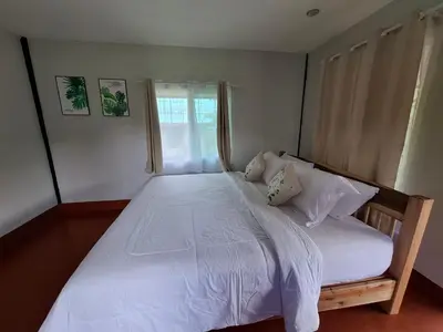 a bedroom with a large white bed with a window at The Best Bungalow in Ban Bang Chak