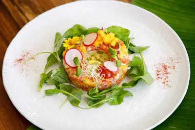 a white plate topped with a salad with food on it at CC's Hideaway Kata - SHA Plus in Kata Beach