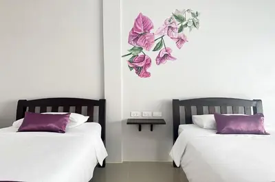 two beds sitting next to each other with purple pillows at Be Leaf Resort SHA in Thalang