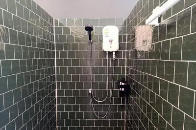a green tiled bathroom with a soap dispenser on a wall at Our Nomad Boutique Hostel in Phuket Town
