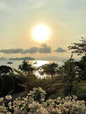 a sun setting over the water with a bunch of flowers at Sunrise Beach Kohyao Resort in Ko Yao Yai