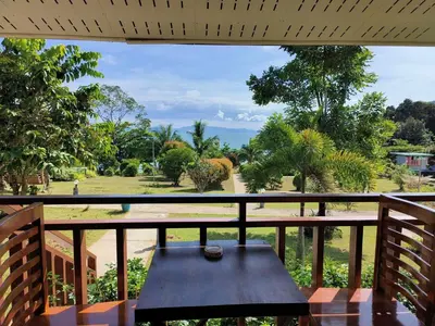 a wooden table on a balcony with a view of a park at Sunrise Beach Kohyao Resort in Ko Yao Yai