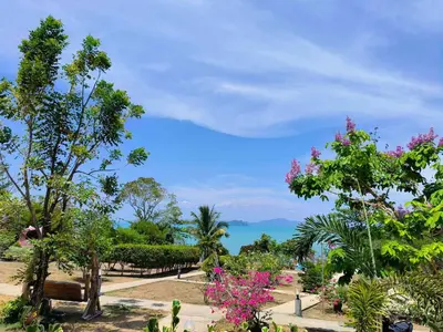 a park with trees and flowers and the ocean at Sunrise Beach Kohyao Resort in Ko Yao Yai